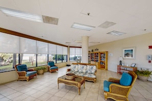 Eine geräumige Lobby mit Korbmöbeln, großen Fenstern und einem Bücherregal.
