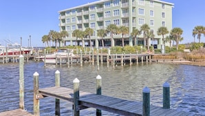A waterfront hotel with a dock, boats, and palm trees. - Bay View Condo w/ Deck, Assigned Boat Slip, WiFi, AC & Shared Pools/Hot Tubs (Fort Morgan)