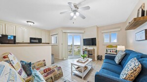 Ein Wohnzimmer mit einer Couch, einem Couchtisch, einem Fernseher und einem Deckenventilator.