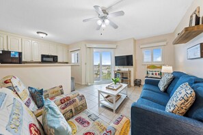 Ein Wohnzimmer mit einer Couch, einem Couchtisch, einem Fernseher und einem Deckenventilator.