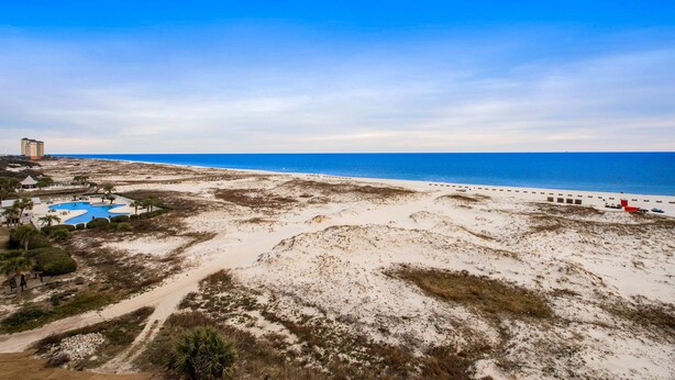Ein Strandresort mit Schwimmbad, Sand und blauem Himmel.