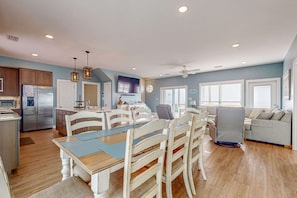 A spacious living area with a dining table, chairs, a sofa, and a kitchen area with a refrigerator and microwave. - Beach & Gulf-Front House with Beach Views, Balcony, Central AC (Fort Morgan)