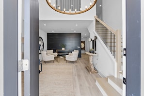 A spacious living area with a modern staircase, a round chandelier, and a large black wall. - Beside Still Waters: Beachfront in MXB, Private Pool, Multiple Suites. (Mexico Beach)