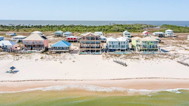 Une propriété située en bord de mer, comprenant plusieurs maisons, une plage de sable et une vue sur l’océan.