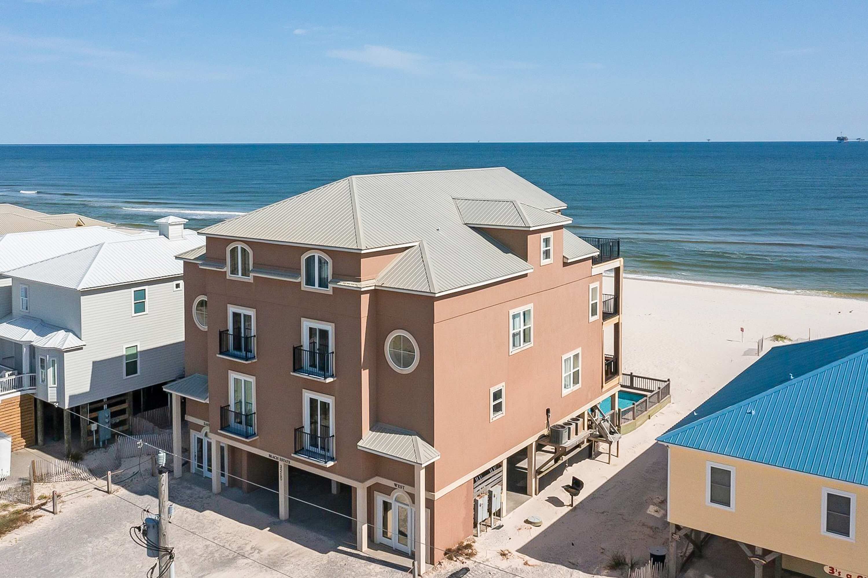A multi-story hotel with a beach view, balconies, and a pool area.