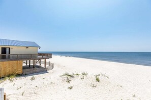 A beach house with a wooden deck and a metal roof, overlooking the ocean. - Bay Walk | Gulf-Front Beach House on Fort Morgan’s Quiet Coast (Fort Morgan)