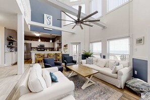 A spacious living area with a ceiling fan, a sofa set, a coffee table, and a kitchen in the background. - Bay Walk | Gulf-Front Beach House on Fort Morgan’s Quiet Coast (Fort Morgan)