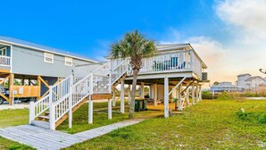 A beachfront property with a wooden deck, a covered outdoor area, and a view of the ocean. - Coastal Living Cottage on Mobile Bay with Private Beach Access (Fort Morgan)
