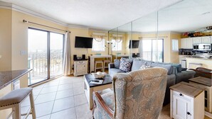 Ein geräumiger Wohnbereich mit Sofa, Esstisch, Küchenzeile und einem Balkon.