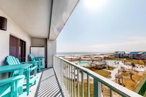 Een balkon met uitzicht op een strand en een zwembad.
