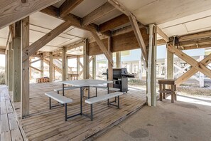 Eine Holzterrasse mit Picknicktischen und einem Grill.