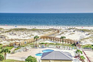 Un resort en la playa con un paseo marítimo de madera, piscina y sillas para tomar el sol.