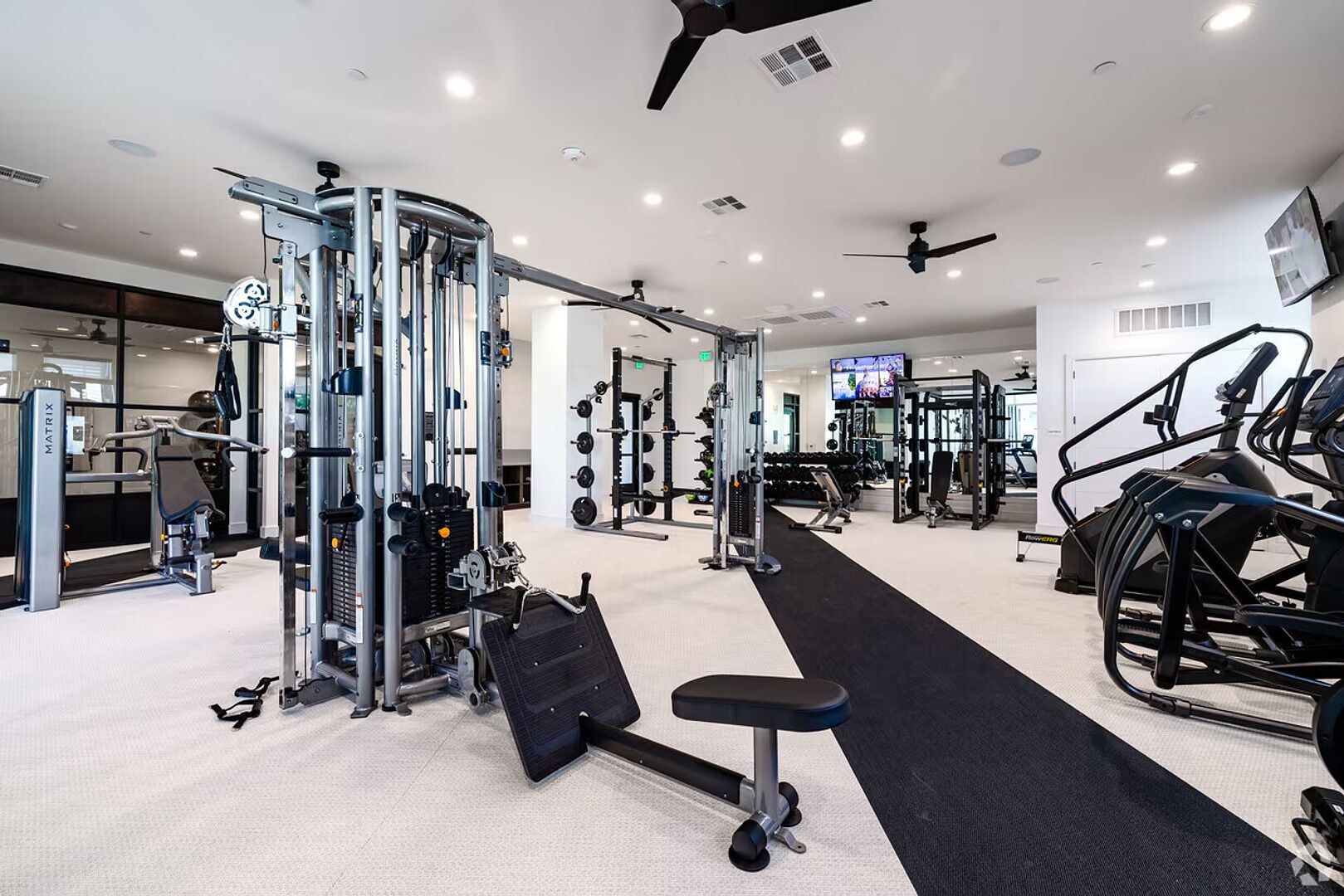 Un gimnasio moderno con diversos equipos de ejercicio, incluyendo máquinas de pesas, una cinta de correr y una banca.