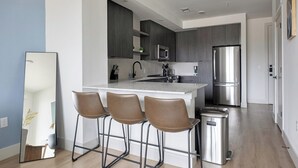 A modern kitchen with a central island, stainless steel appliances, and bar stools. - Landing | Spectacular 1BD, Gym, Rooftop Lounge (Austin)