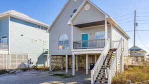 A two-story house with a balcony, a staircase, and a door marked with the number 105. - Dog-friendly house with private pool - dock and fishing pier available (Gulf Shores)