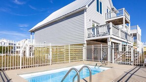 A swimming pool with a metal ladder, a white fence, and a two-story building with balconies. - Dog-friendly house with private pool - dock and fishing pier available (Gulf Shores)