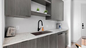 Eine moderne Küche mit integriertem Geschirrspüler, einer Spüle und einer Kaffeemaschine.