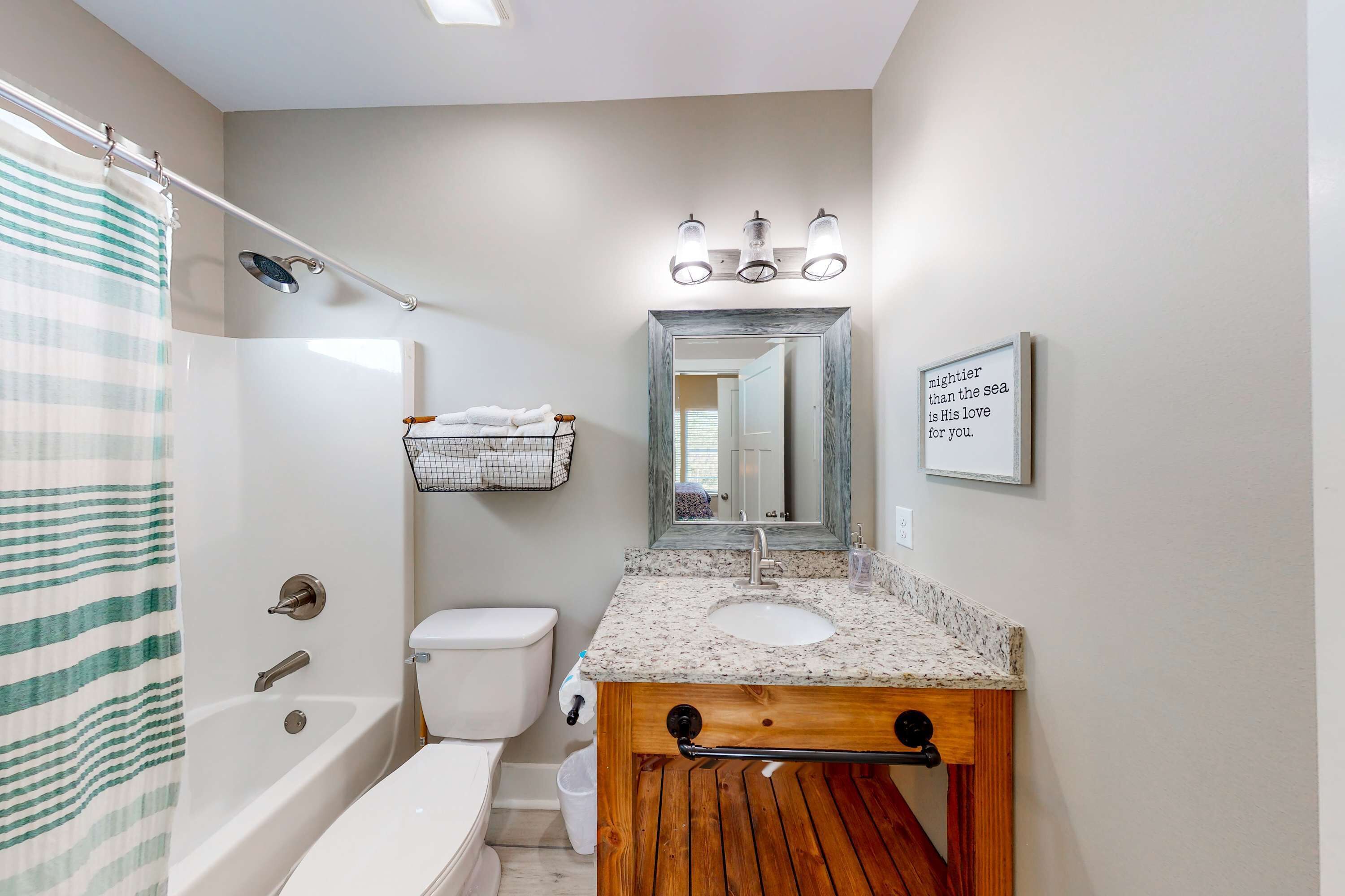 A bathroom with a bathtub, toilet, vanity with a sink, and a shower curtain.