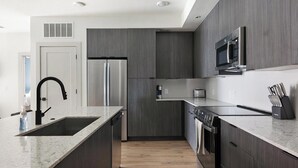 A modern kitchen with a stainless steel refrigerator, a microwave, and a dishwasher. - Landing | Beautiful 2BD, Rooftop Lounge, Gym (Austin)