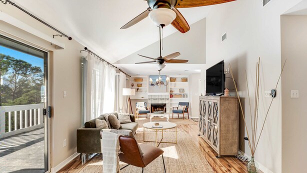 A spacious living room with a ceiling fan, a fireplace, a television, and a balcony. - Newly renovated, bright & chic Home with private deck, grill & near the beach (Fort Morgan)