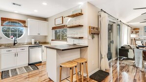 A modern kitchen with white cabinets, a wooden island, and stools. - Newly renovated, bright & chic Home with private deck, grill & near the beach (Fort Morgan)