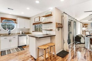 A modern kitchen with white cabinets, a wooden island, and stools. - Newly renovated, bright & chic Home with private deck, grill & near the beach (Fort Morgan)
