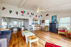Amplia sala de estar con mesa de comedor, sillas, sofá y zona de cocina.