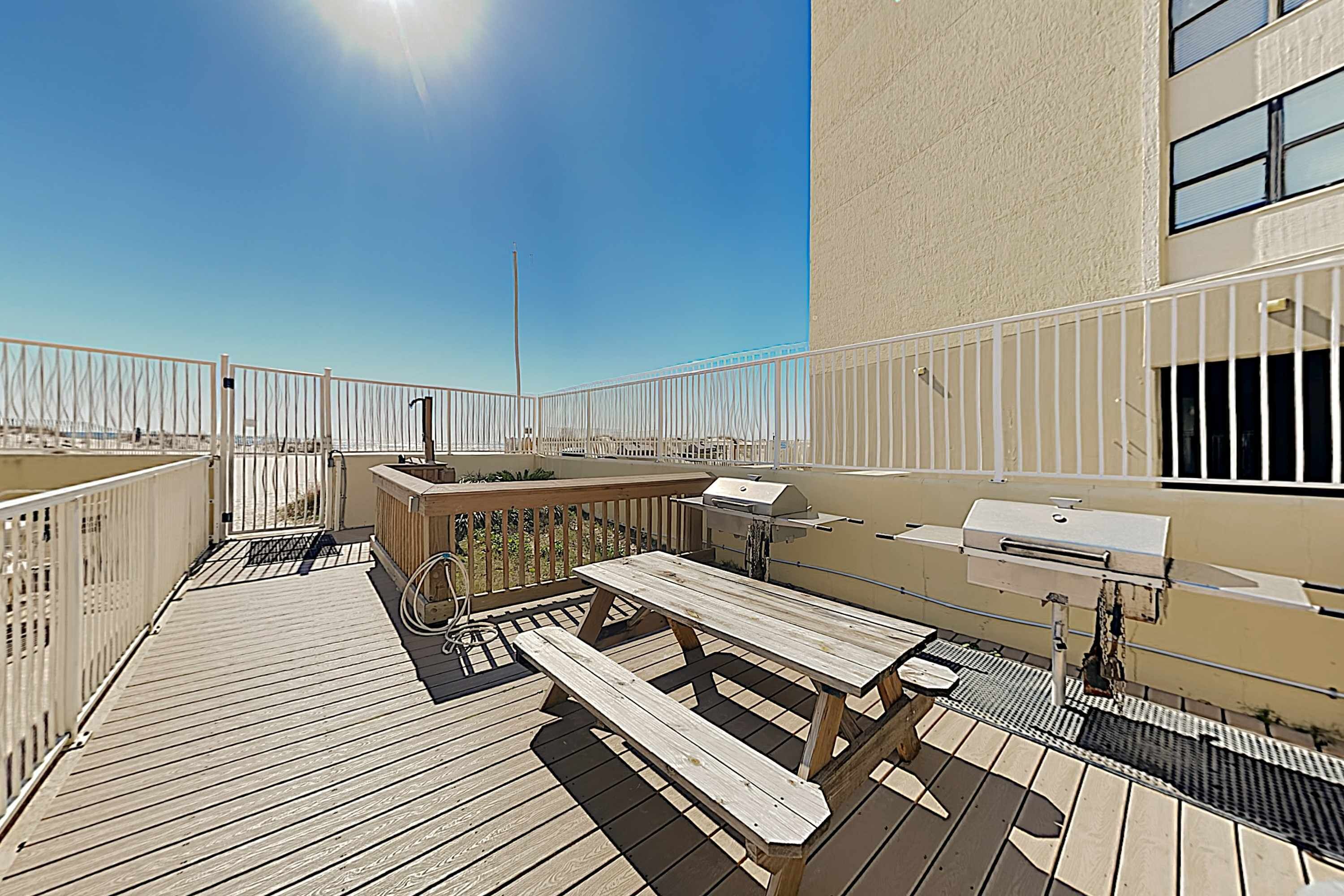 Una terraza en la azotea con una parrilla, una mesa de picnic y zona de estar al aire libre.