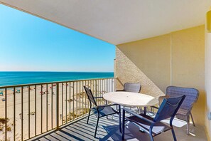Un balcon avec une table et des chaises, donnant sur une plage.
