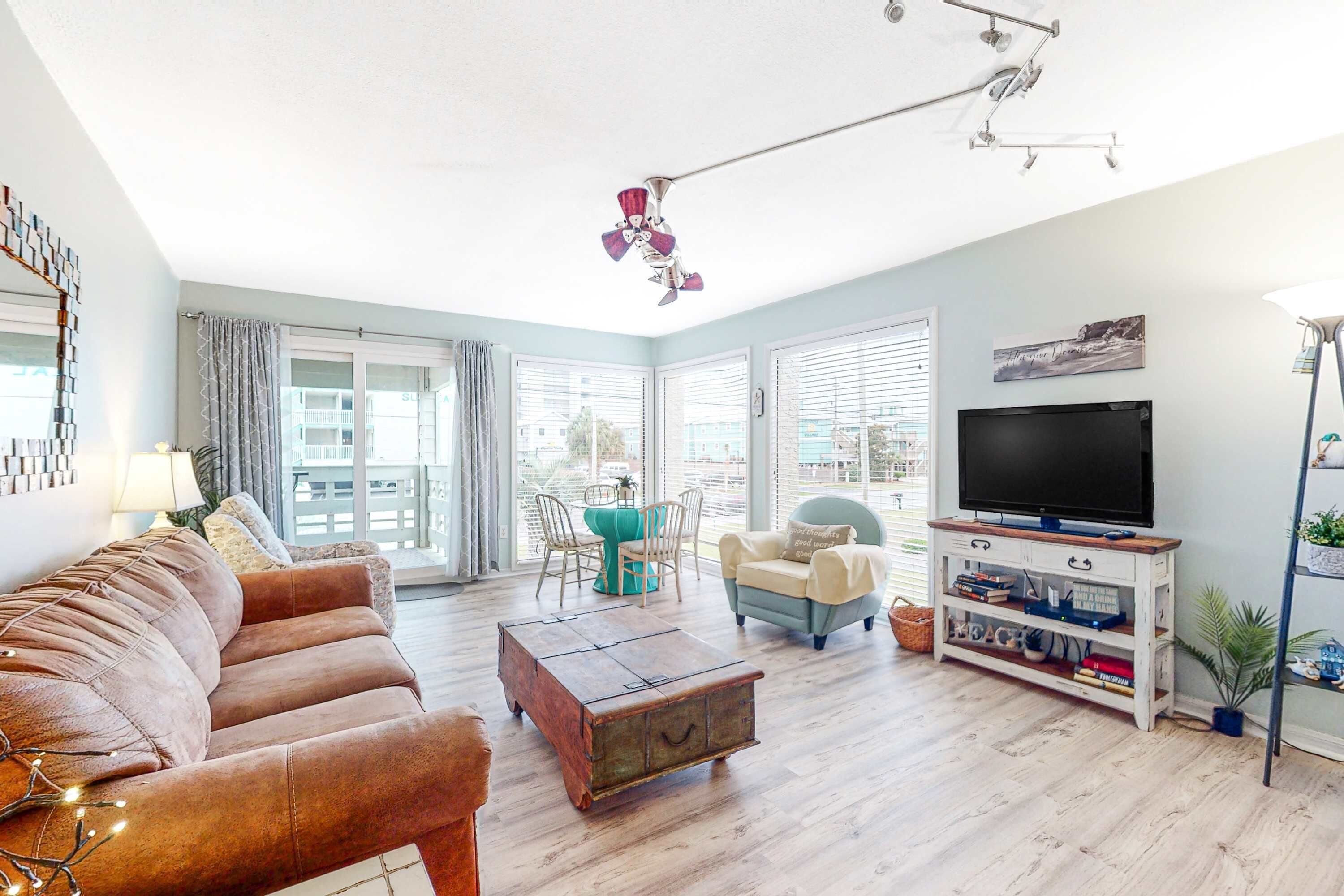 A living room with a sofa, a coffee table, a TV stand, and a ceiling fan.