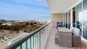 En balkong med utsikt över en swimmingpool och strandhus.