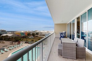 Ein Balkon mit Blick auf ein Schwimmbecken und Strandhäuser.