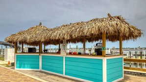 A beachside bar with thatched umbrellas and a turquoise counter. - Brilliant water view condo with multiple pools, lazy river & internet (Orange Beach)
