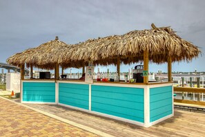 A beachside bar with thatched umbrellas and a turquoise counter. - Brilliant water view condo with multiple pools, lazy river & internet (Orange Beach)