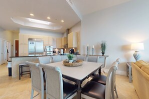 A modern kitchen with a central island, built-in appliances, and a dining area with a table and chairs. - Brilliant water view condo with multiple pools, lazy river & internet (Orange Beach)