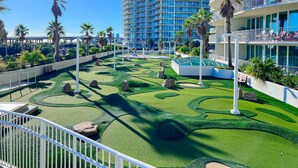 A resort with a pool area, palm trees, and a multi-story building with balconies. - Brilliant water view condo with multiple pools, lazy river & internet (Orange Beach)