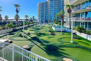 A resort with a pool area, palm trees, and a multi-story building with balconies. - Brilliant water view condo with multiple pools, lazy river & internet (Orange Beach)