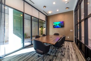 A conference room with a large table, black chairs, a TV on the wall, and large windows. - Landing | Chic Studio, Rooftop Lounge, Game Room (Austin)