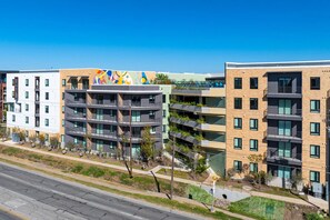 A multi-story building with a modern architectural design, featuring balconies and large windows. - Landing | Chic Studio, Rooftop Lounge, Game Room (Austin)