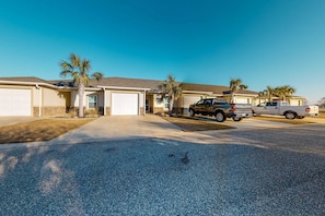 A residential street with houses, a driveway, and parked vehicles. - Dog-Friendly Condo with Shared Pool, Central AC, & Free High-Speed WiFi (Gulf Shores)