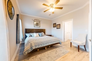 A bedroom with a bed, a ceiling fan, a door, and a chair. - Dog-Friendly Condo with Shared Pool, Central AC, & Free High-Speed WiFi (Gulf Shores)