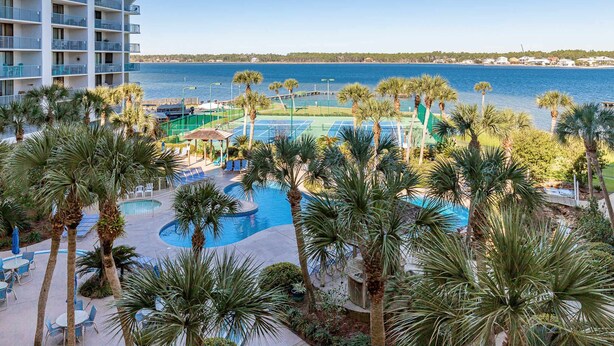 A hotel with a pool, outdoor seating, and a view of the water. - Inviting Condo w/ Shared Pools, Hot Tub, Tennis, & Beach Access (Gulf Shores)