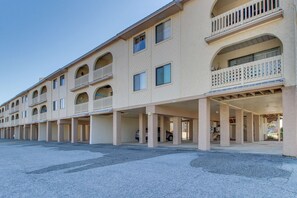 Un hôtel à plusieurs étages doté de balcons, d’un parking couvert et offrant une vue sur un ciel dégagé.