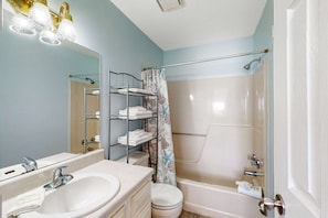 Une salle de bain équipée d’un lavabo, d’un miroir, d’une douche et d’un porte-serviettes.