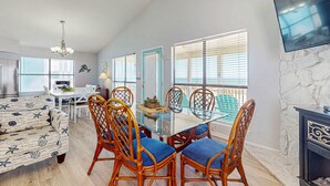 A dining area with a glass table, wicker chairs, and a sofa. - Spacious, Gulf-front vacation home with covered deck & beach access (Gulf Shores)