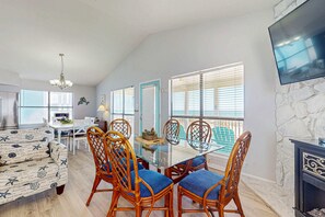 A dining area with a glass table, wicker chairs, and a sofa. - Spacious, Gulf-front vacation home with covered deck & beach access (Gulf Shores)
