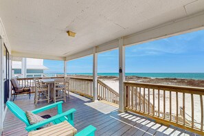 A wooden deck with a table and chairs, a bench, and a view of the beach. - Spacious, Gulf-front vacation home with covered deck & beach access (Gulf Shores)