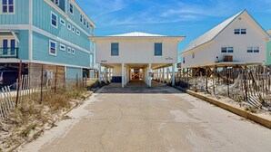 A beachfront property with a covered walkway, a two-story building, and a single-story house. - Spacious, Gulf-front vacation home with covered deck & beach access (Gulf Shores)