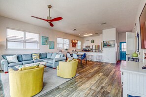 A spacious living room with a sofa, ottoman, and dining area. - Memorable & group-friendly house w/Gulf views and private sun deck (Gulf Shores)