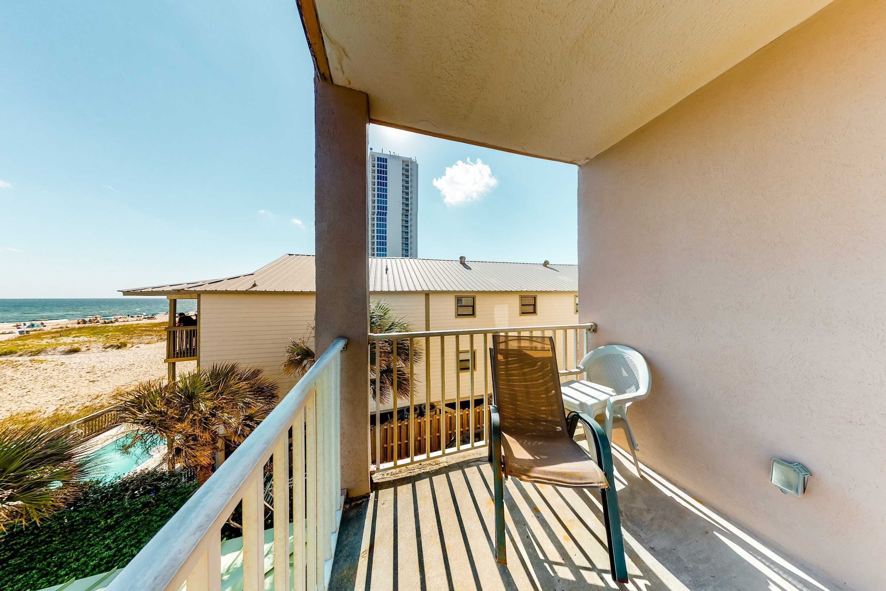 Ein Balkon mit Blick auf den Strand, ein Pool und ein hohes Gebäude im Hintergrund.